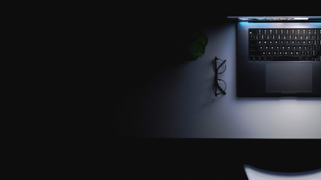 Leuchtender Laptop auf einem dunklen Schreibtisch als Symbol für KI im Webdesign