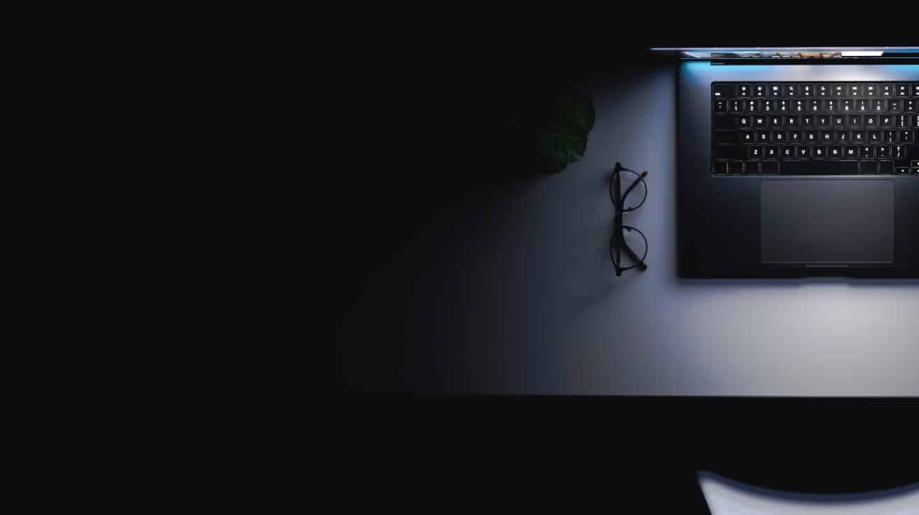 Leuchtender Laptop auf einem dunklen Schreibtisch als Symbol für KI im Webdesign