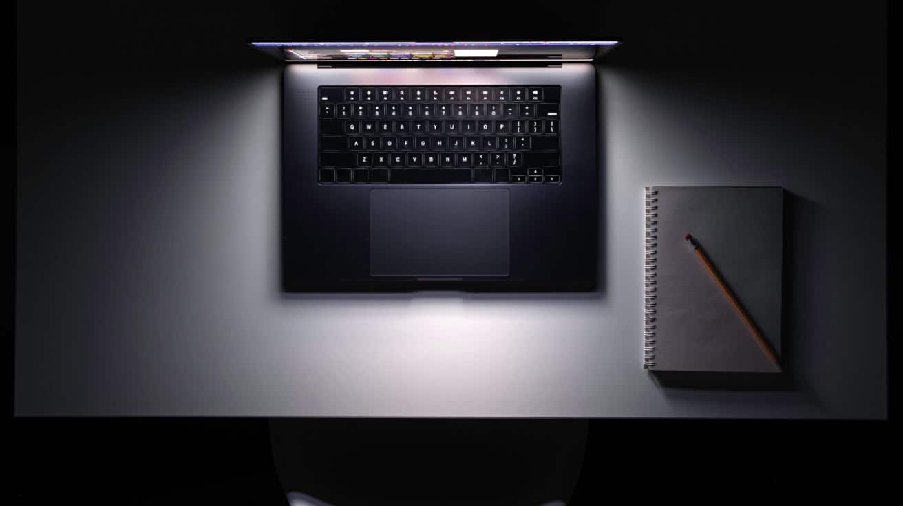 Aufgeklappter Laptop mit Notizbuch von oben auf dunklem Schreibtisch als Symbol fuer Sichtbarkeit in ChatGPT und Google AI Overviews