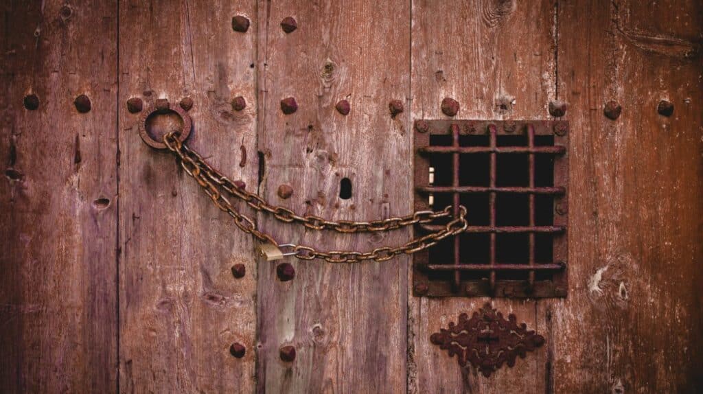 Alte Holztür mit rostiger Kette und Vorhängeschloss als Sinnbild für eine abgesicherte Website