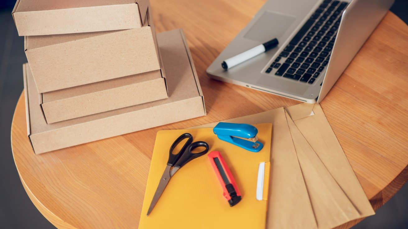 Verpackungsmaterial, Kartons und ein Laptop auf einem Holztisch – Versandvorbereitung für einen kleinen Onlineshop